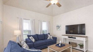 Un salon comprenant un canapé, une table basse, un téléviseur et un ventilateur de plafond.