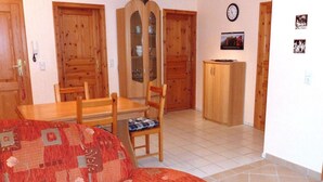 Un saló acollidor amb un sofà, taula de dinar de fusta, cadires i un armari.