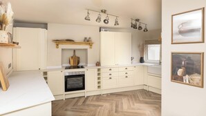 Una cocina moderna con armarios blancos, horno empotrado e iluminación colgante.