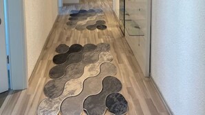 A hallway with a patterned floor, a glass display case, and a door at the end. - Baba Apart 1 Große, Moderne Wohnung Direkt an der Schweizer Grenze (Laufenburg)