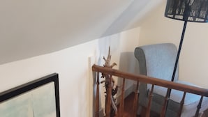 A staircase with a wooden handrail, a wall-mounted picture, and a blue door.