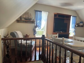 A cozy living room with a wooden staircase, a white table, and a television.