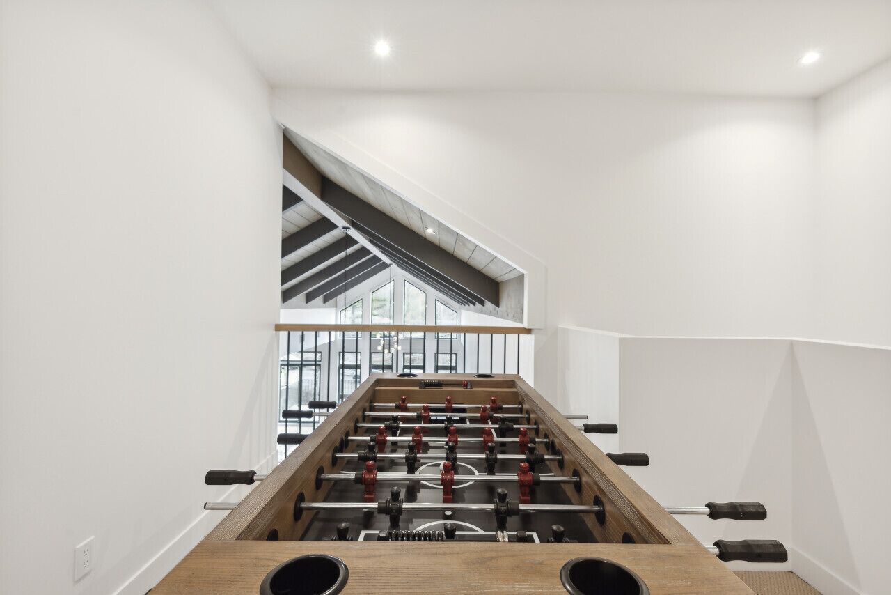 Une pièce moderne équipée d’un baby-foot, d’un escalier et d’une grande fenêtre.