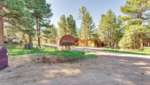 A sign for 'Redwood The Commons' with a gravel driveway and surrounding trees. - Easy Resort Access: Angel Fire Adventure Condo! (Angel Fire)