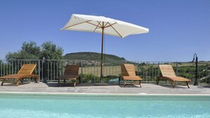 A poolside area with three wooden lounge chairs and a white umbrella. - Lubagnu Vacanze (Castelsardo)