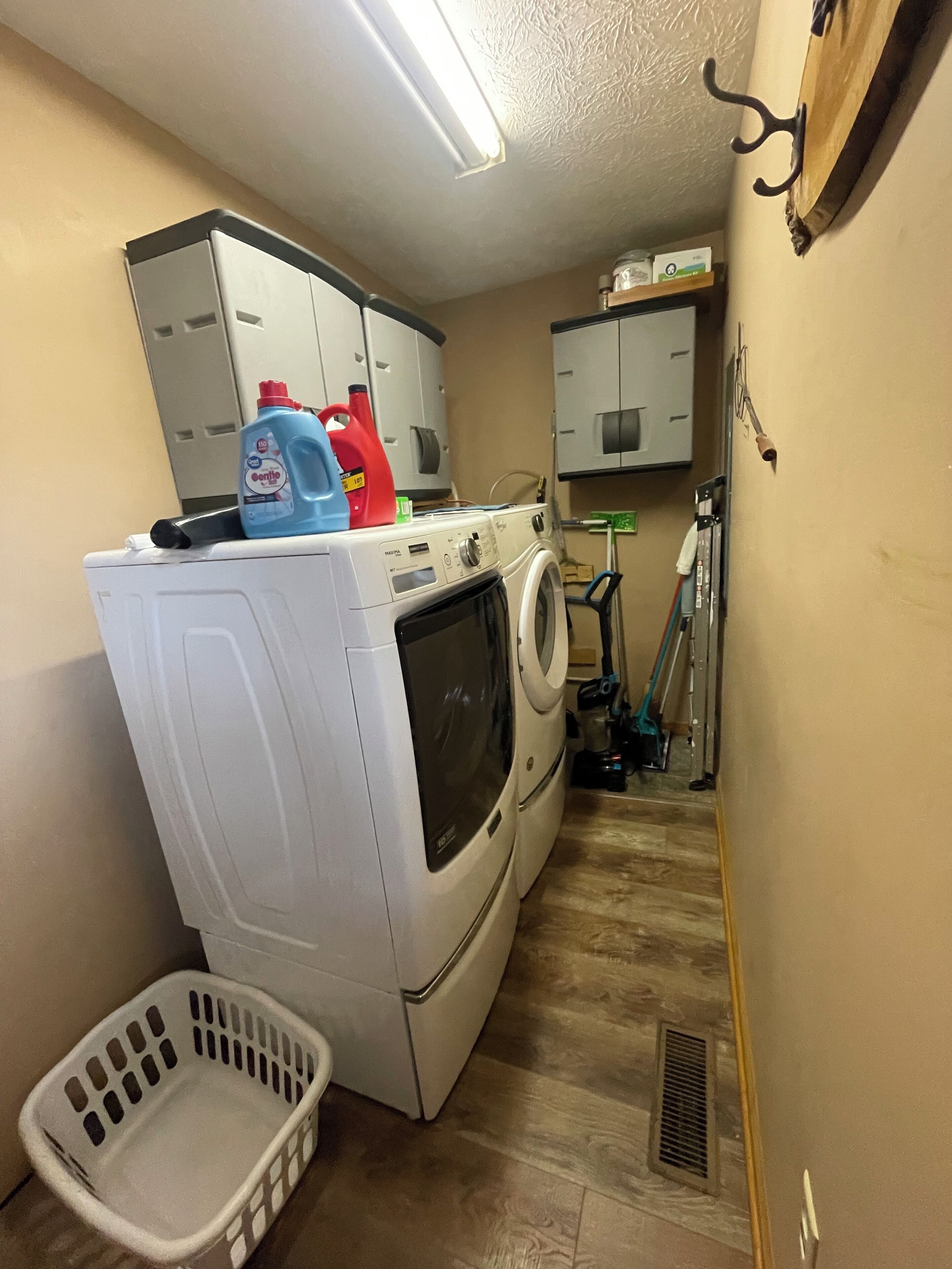 Un cuarto de lavandería con lavadora, secadora y un carro de utilidades.