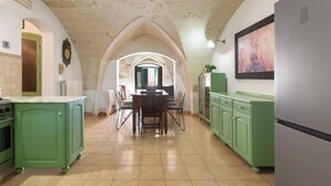 A kitchen with green cabinets, a wooden dining table, and a large refrigerator.