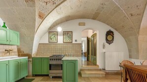 A kitchen with green cabinets, a stove, and a clock on the wall.
