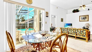Un'area pranzo con un tavolo in vetro e sedie, un divano e una TV.