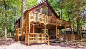 A cabin with a wooden deck, a stone chimney, and a porch with steps leading to a second-story balcony. - Walk to Lake Harmony l FREE Beach Access l Hot Tub (Lake Harmony)