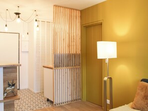 Ein Zimmer mit Holzboden, einer Lampe, einem Bett mit Kissen, einer Holzwand und einem gemusterten Teppich.
