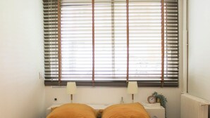 A bedroom with a bed, two bedside lamps, a clock, and a radiator.