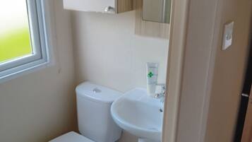 A compact bathroom with a toilet, sink, and a small trash bin.