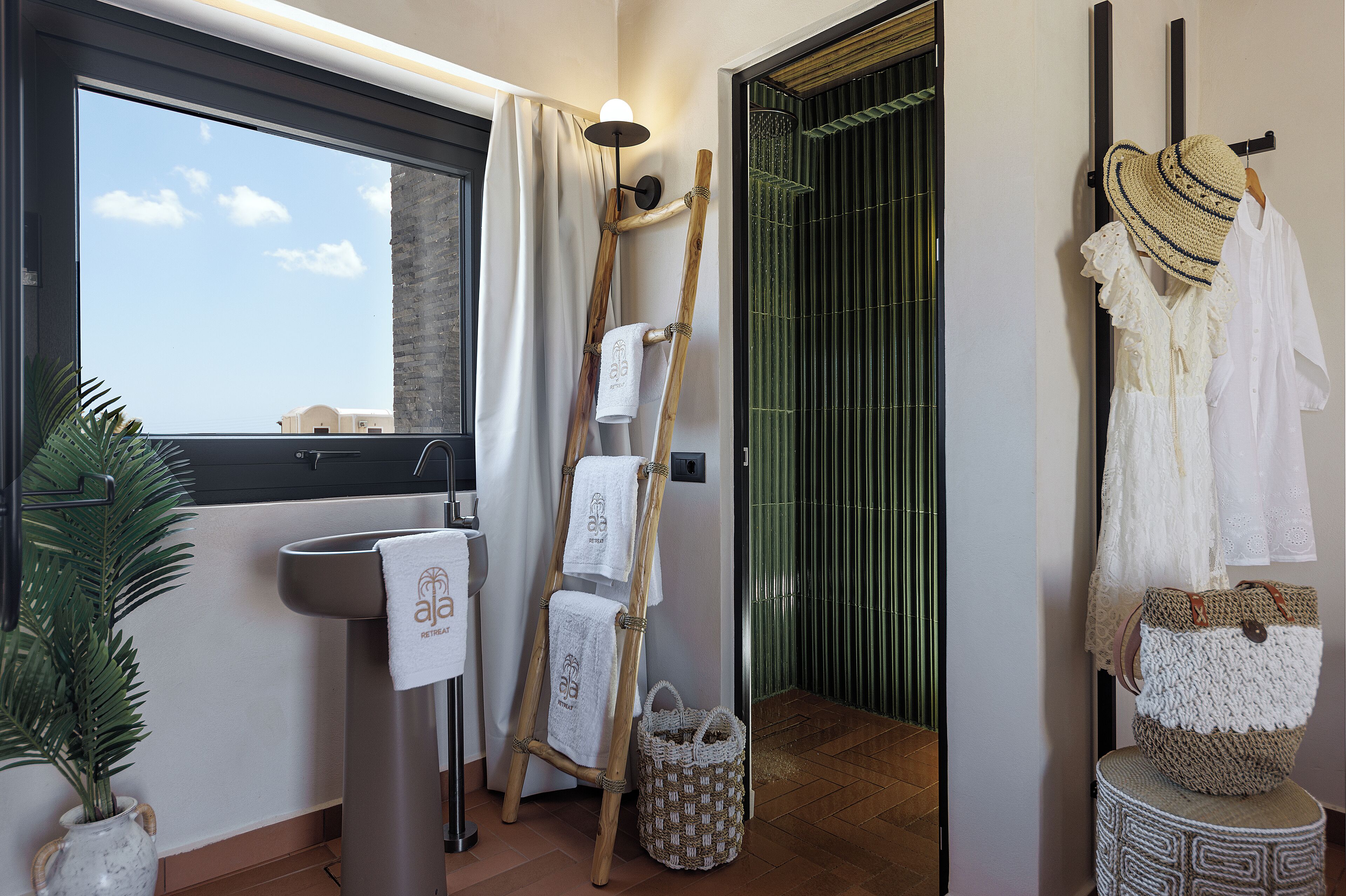 Ein Badezimmer mit großem Fenster, einem Handtuchhalter, einer Holzleiter und einer gewebten Tasche.