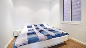 A bedroom with a bed, a window, and a nightstand. - Haus Meeresloft - FW 3 (Norderney)