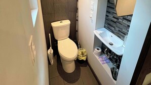 A compact bathroom with a toilet, sink, and a towel rack.