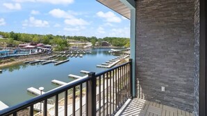 Un balcon donnant sur une rivière, des bateaux amarrés et un bâtiment situé au loin.