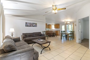 A spacious living room with a sofa set, a coffee table, and a dining area with chairs and a table.