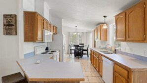 A modern kitchen with wooden cabinets, a central island, and a dining area with a table and chairs.