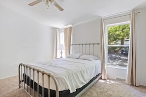 A bedroom with a bed, a window, and a ceiling fan.