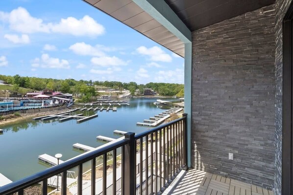 A balcony with a view of a river, docked boats, and a distant building.