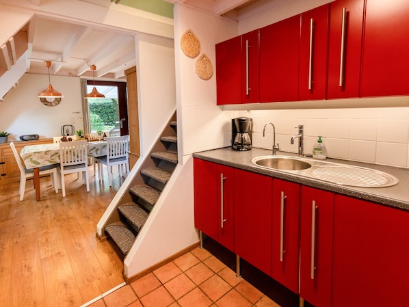 A kitchen with red cabinets, a sink, and a coffee maker. - Cozy Garden Retreat in Lanaken (Lanaken)