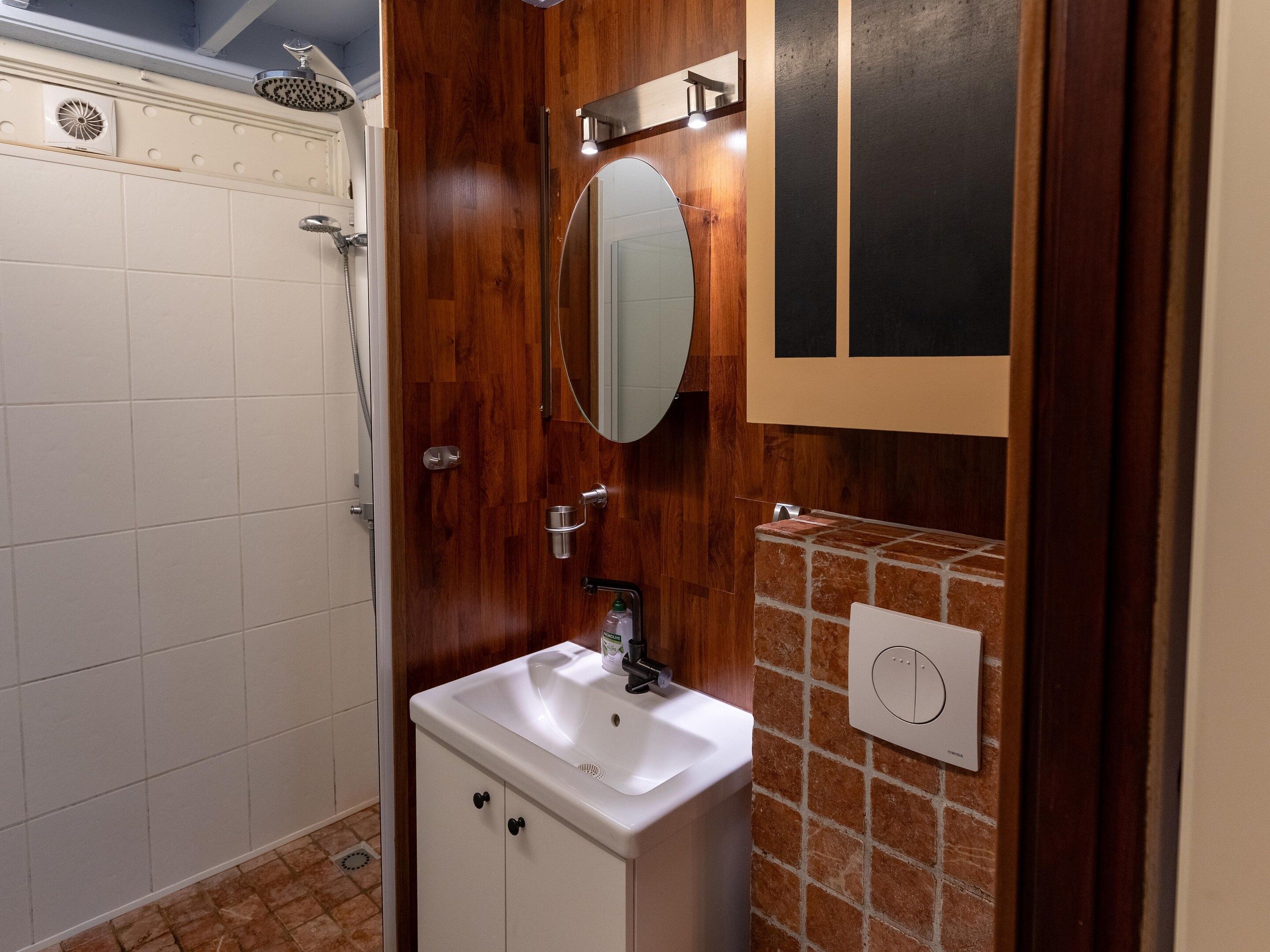 A bathroom with a shower, a sink, a mirror, and a towel rack.