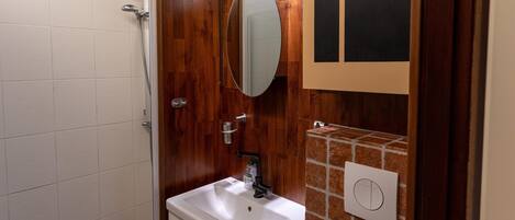 A bathroom with a shower, a sink, a mirror, and a towel rack.