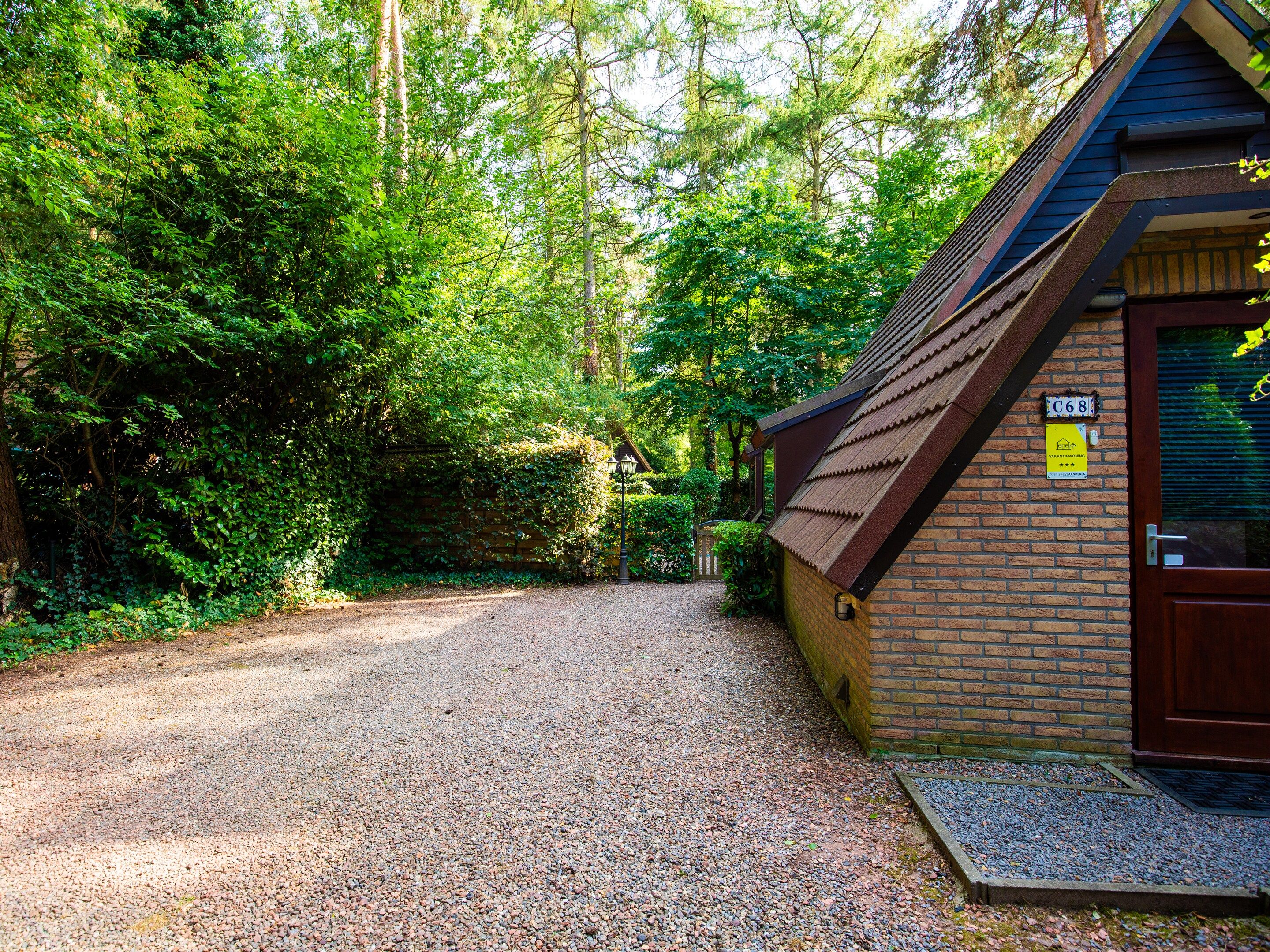 A gravel driveway leading to a brick building with a dark brown door and a small porch.