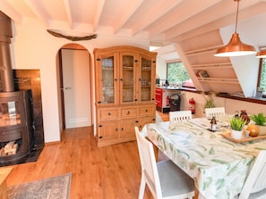 A cozy kitchen with wooden cabinets, a dining table with chairs, and a fireplace. - Cozy Garden Retreat in Lanaken (Lanaken)
