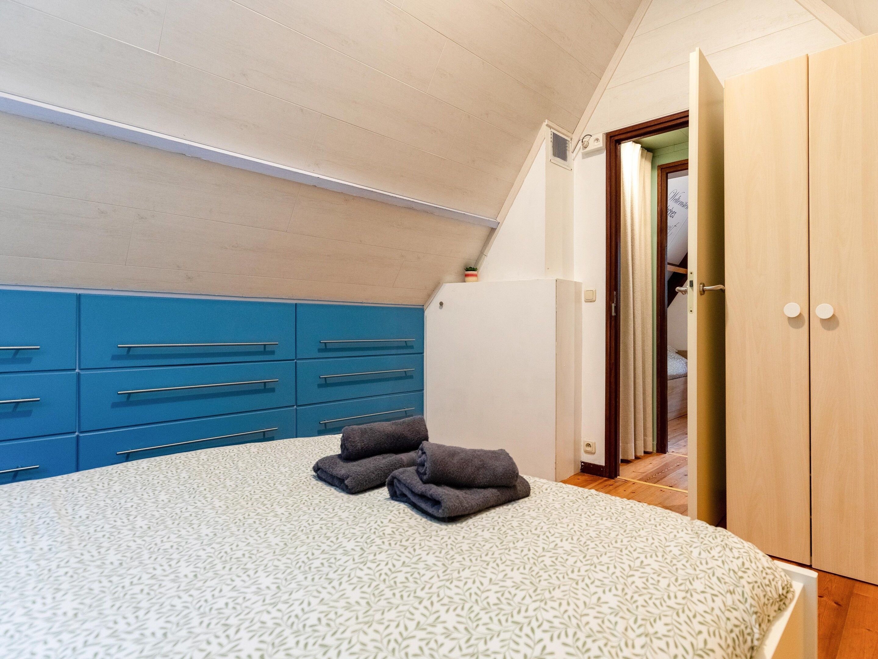 Une chambre à coucher avec un lit, une commode bleue et une armoire en bois.