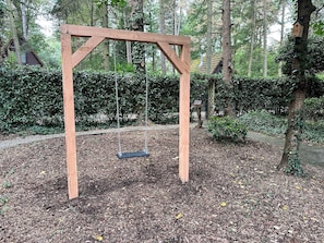 A wooden swing set in a wooded garden area. - Cozy Garden Retreat in Lanaken (Lanaken)