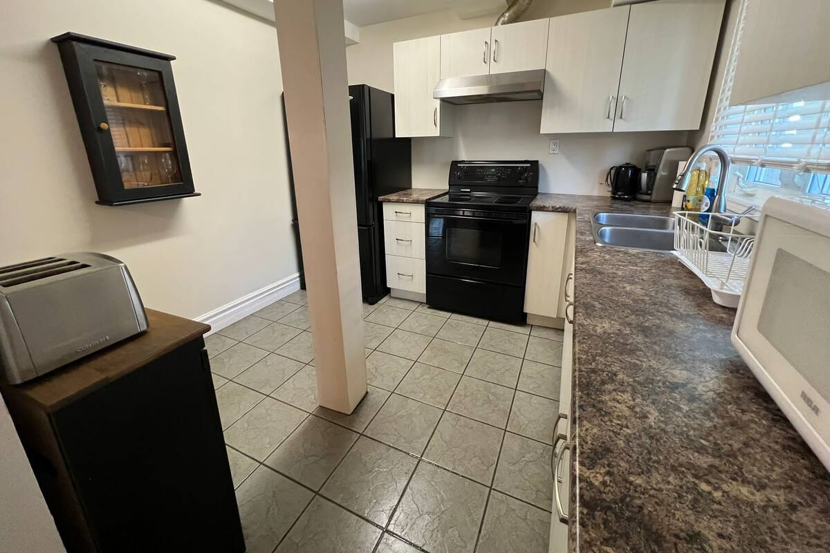 A kitchen with a black stove, white cabinets, and a granite countertop.