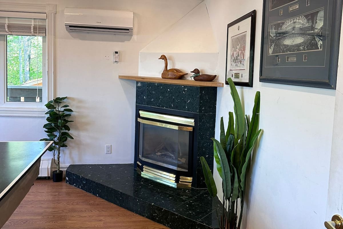 A modern living room with a fireplace, a mounted air conditioner, and a framed picture on the wall.