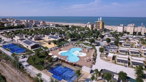 Una zona residencial costera con una gran piscina, varios edificios y una playa al fondo.