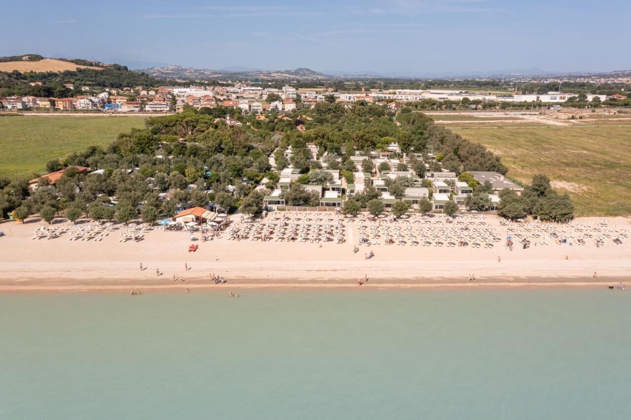 Une station balnéaire dotée de plusieurs hébergements de type bungalow, d’une plage de sable et offrant une vue sur la mer.