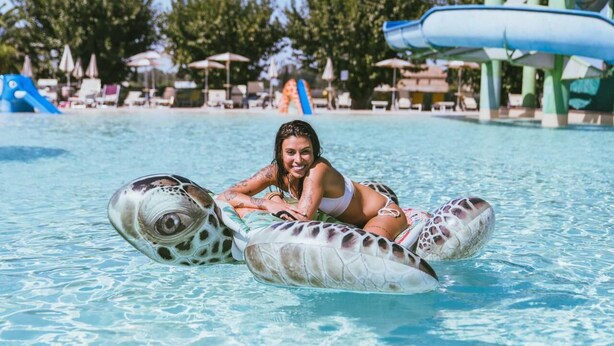 A person in a pool using a turtle float.