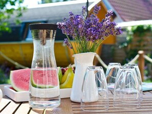 A table with a clear glass pitcher, a white pitcher, a vase with purple flowers, and several empty glasses. - Holiday Home Bloom 2 (Zingst)