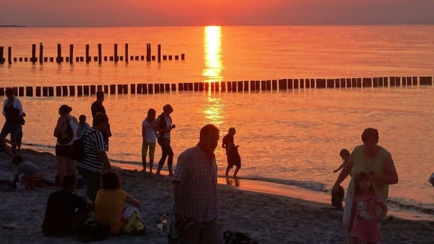 A beach at sunset with people walking and sitting on the sand. - Holiday Home Bloom 2 (Zingst)
