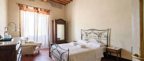 A bedroom with a bed, a chair, a desk, and a mirror.