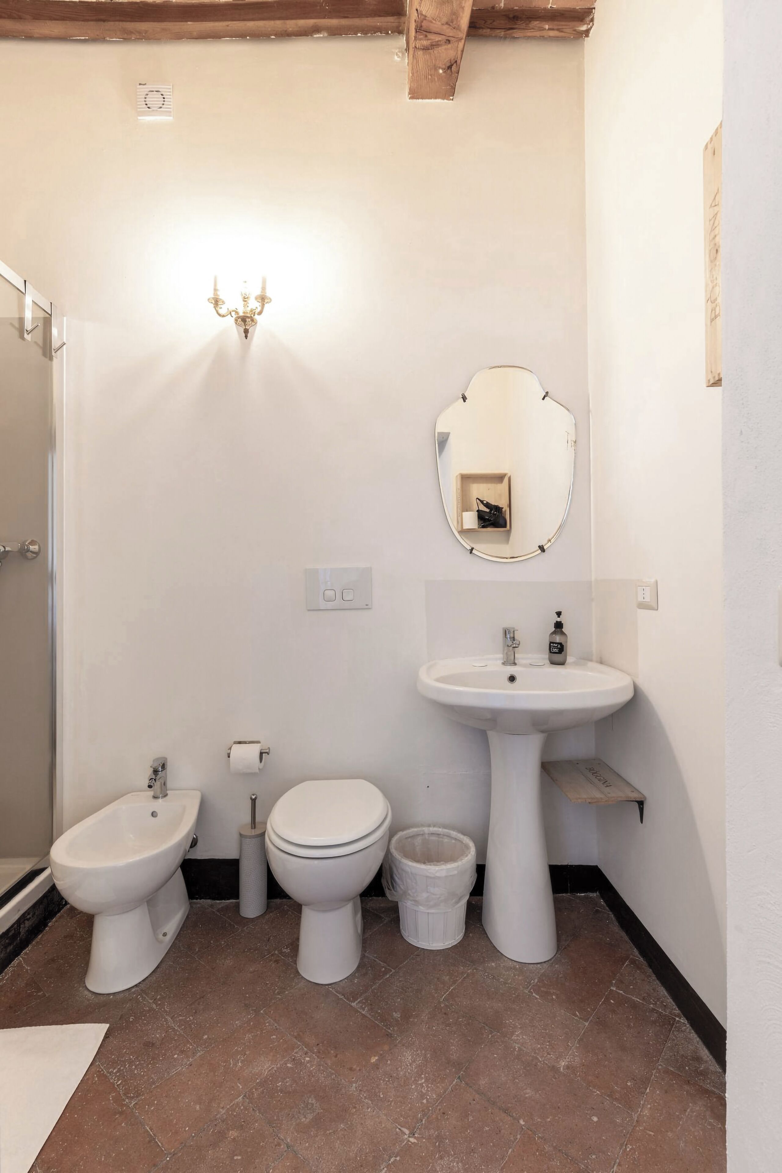 A bathroom with a bidet, toilet, sink, and a mirror.