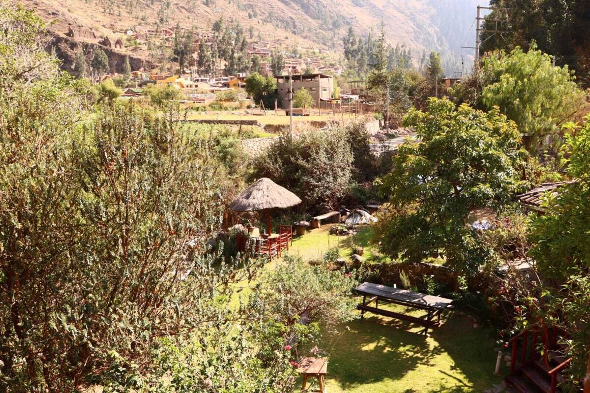 A rural village with traditional houses, a thatched-roof hut, and lush greenery.