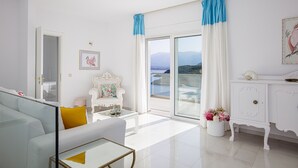 Un salon lumineux avec un canapé blanc, un fauteuil blanc, une table basse en verre et un meuble blanc.