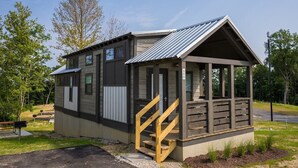 A small, two-story cabin with a metal roof and a wooden porch. - Cincinnati Camp Cedar (Mason)