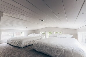 A bedroom with two beds, a sloped ceiling, and large windows. - Cincinnati Camp Cedar (Mason)