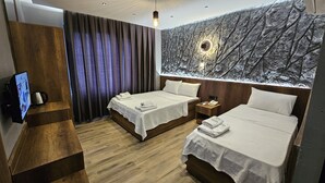 A hotel room with two beds, wooden flooring, a large wall mural, a TV, and a wooden side table. - Rever Hotel (Sanliurfa)
