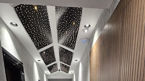 A modern hallway with a tiled floor, a wooden panel wall, and a ceiling with a starry design. - Rever Hotel (Sanliurfa)