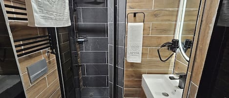 A bathroom with a shower, toilet, and sink. There is a towel rack with a towel hanging on it, and a towel hanging on the wall.