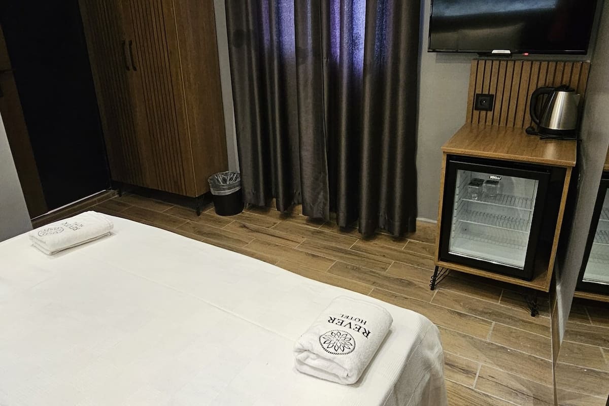 Une chambre d’hôtel équipée d’un lit, d’une télévision, d’un système de climatisation et d’un mini-bar.