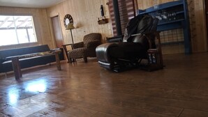 Ein Zimmer mit Holzwänden, einem Massagesessel, einer Bank und einem blauen Regal mit Gläsern.